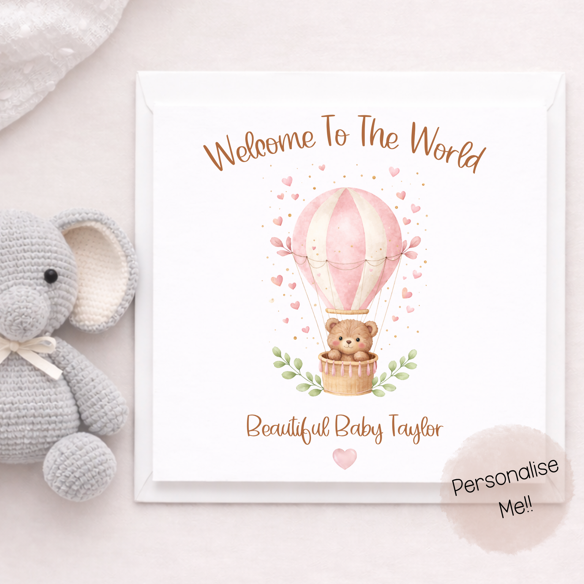 Baby shower card with teddy bear and hot air balloon illustration, accompanied by a plush elephant toy.