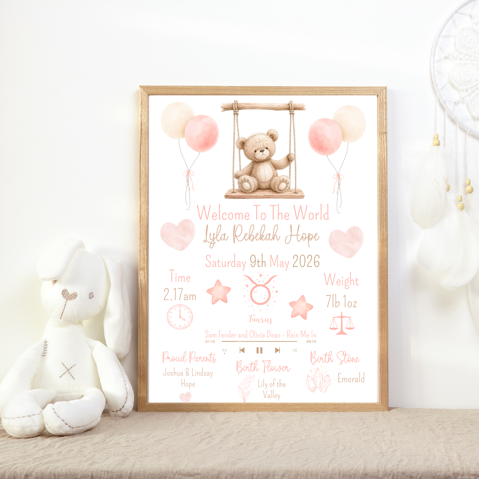 Framed birth announcement poster with teddy bear and balloons on a shelf with toys.