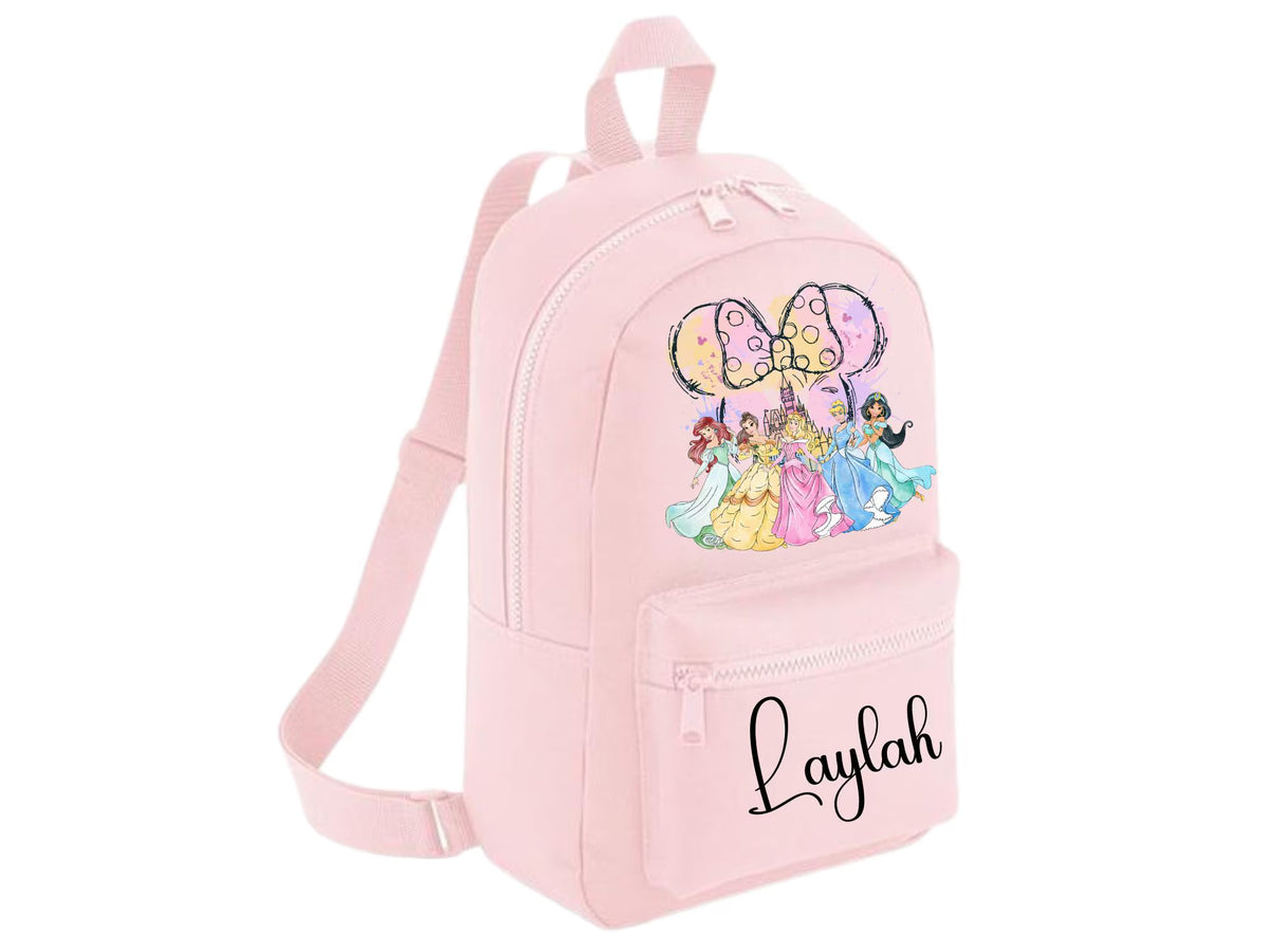 A light pink mini backpack with a front zippered pocket featuring the name 'Laylah' in black script. The main body has a colorful graphic of Disney princesses under a large bow.